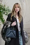 Jennifer Lawrence poserer i svart kåpe med pelsdetaljer og svart Dior-veske i Paris.