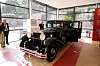 Svart historisk pavemobil utstilt på rød plattform i Vatikanmuseene.