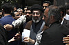 Mojtaba Khamenei i svart turban holder papirer, omgitt av menn under Quds-markeringen i Teheran.