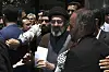 Mojtaba Khamenei i svart turban holder papirer, omgitt av menn under Quds-markeringen i Teheran.