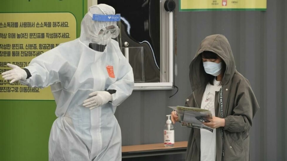 En helsearbeider i hovedstaden Seoul viser vei til en teststasjon for coronaviruset. Sør-Korea rapporterer at 133 personer som tilsynelatende var friske av viruset, har testet positivt på nytt.
