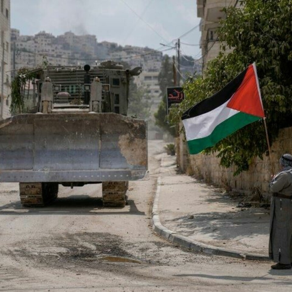 En palestinsk demonstrant foran en av bulldoserne som den israelske hæren benytter for å rive bolighus og ødelegge infrastruktur på den okkuperte Vestbredden. Oljefondet har investeringer i flere selskap som leverer slike anleggsmaskiner til den israelske hæren.