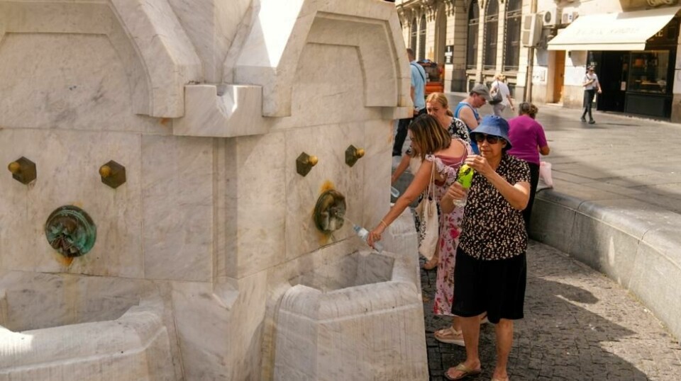 Beboere og turister fyller opp vannflaskene fra en fontene i Beograd. Flere land på Balkan er rammet av en hetebølge som førte til strømbrudd fredag. Foto: Darko Bandic / AP / NTB