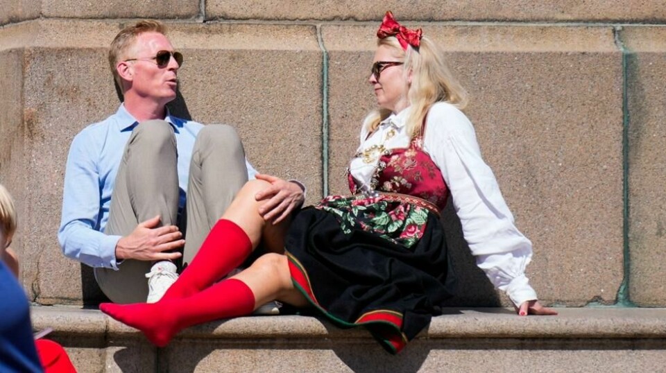 Det er godt og varmt i Oslo fredag. Cecilie Schibstad med røde strømper og Jon Gløersen fra Risør lufter føttene ved Karl Johan-statuen utenfor slottet. Foto: Heiko Junge / NTB