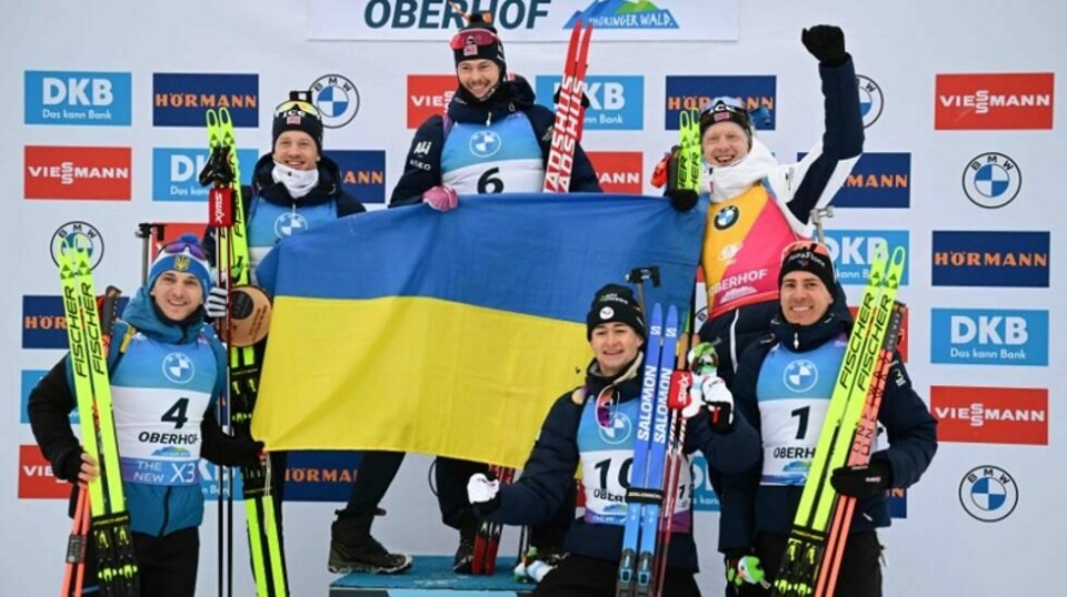 Ukrainas Dmytro Pidruchnyi feirer sammen Tarjei Bø, Sturla Holm Lægreid, Frankrikes Eric Perrot, Johannes Thingnes Bo og Frankrikes Quentin Fillon Maillet med et ukrainsk flagg på pallen etter mennenes 12,5 kilometer jaktstart i Oberhof 11. januar 2025.