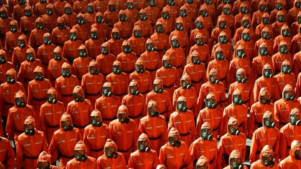 I tillegg til militær deltok nordkoreanere ikledd oransje smitteverndrakter under nattens markering. I tillegg til militær deltok nordkoreanere ikledd oransje smitteverndrakter under nattens markering. Foto: STR / KCNA VIA KNS / AFP