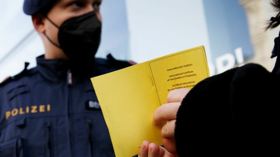 En politibetjent sjekker vaksinasjonsstatusen til en østerriker ved inngangen til et kjøpesenter i Wien. Landet har innført lockdown for landets to millioner uvaksinerte innbyggere.