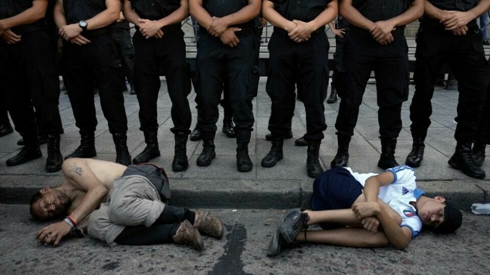 Politiet står på rekke og rad for å beskytte nasjonalforsamlingen i Buenos Aires samtidig som demonstranter har lagt seg ned som ledd i protesten mot den økonomiske politikken til landets nye president. Foto: Rodrigo Abd / AP / NTB
