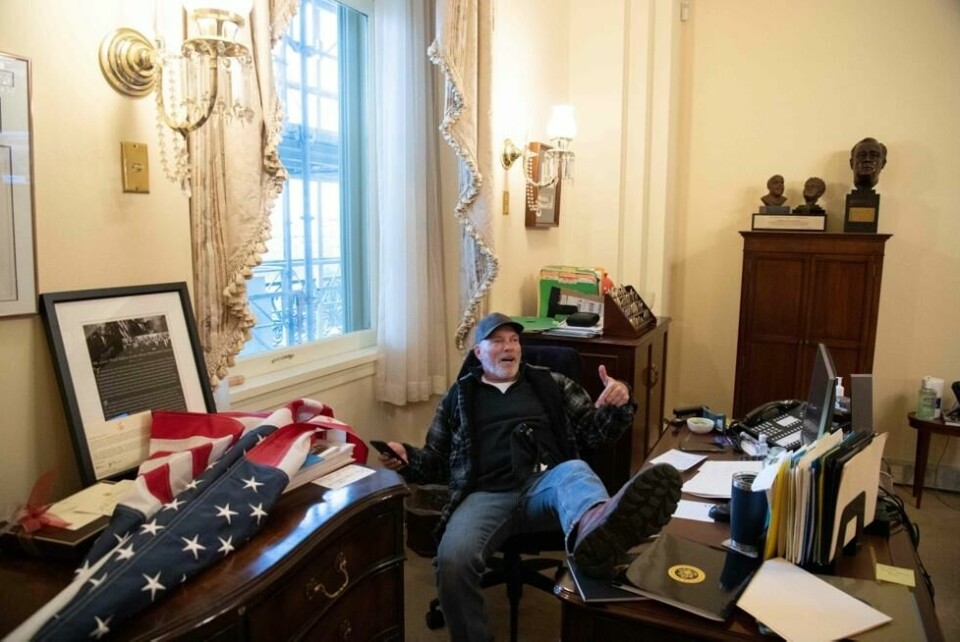 Richard Barnett (60) har beina på skrivebordet til speaker Nancy Pelosi under stormingen av Kongressen i USA onsdag. Richard Barnett (60) har beina på skrivebordet til speaker Nancy Pelosi under stormingen av Kongressen i USA onsdag. Foto: Saul Loeb / AFP