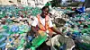 En kvinnelige plastinnsamler i Haiti samler inn plastflasker. Foto: Plastic Bank