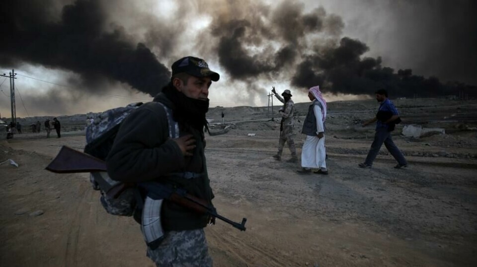 Soldat fra militsgruppen «Den folkelige mobiliseringsstyrken» holder vakt øst for Mosul, mens fordrevne irakiske familier flykter fra de urolige områdene, 22. oktober 2016.