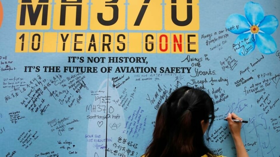 En kvinne skriver en hilsen på en minnevegg i anledning at det er ti år siden passasjerflyet MH370 forsvant sporløst kort tid etter avgang fra Kuala Lumpur. Foto: FL Wong/AP/NTB