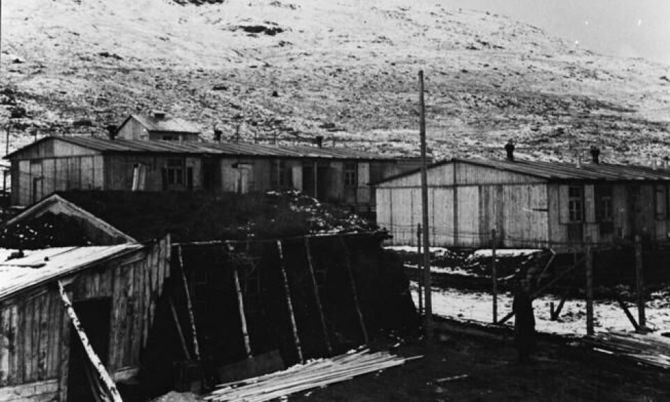 Bildet viser viser de to fangebrakkene i leiren. Det var disse som hadde blitt hentet fra Middavarre gruver. I forkant sees en torvisolert vaktbrakke for tyskerne og bak brakkene kan man skimte vaskehuset. Foto: Nord-Troms Museum Bildet viser viser de to fangebrakkene i leiren. Det var disse som hadde blitt hentet fra Middavarre gruver. I forkant sees en torvisolert vaktbrakke for tyskerne og bak brakkene kan man skimte vaskehuset. Foto: Nord-Troms Museum