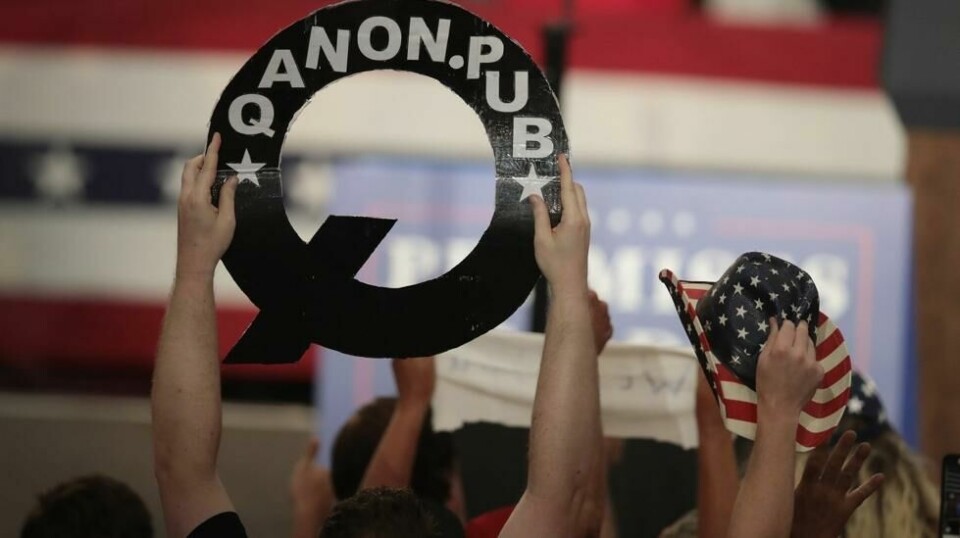 Donald Trumps tilhengere viser logoen til QAnon - en konspirasjonsteori omhandler en konspirasjonsteori om en «stat i staten» med forbindelsert til Hollywood og Demokrater som driver med alt mulig fra pedofili til statskupp.