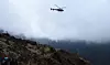 Et helikopter flyr over flere turgåere i fjellet som holder til ved Everest Base Camp. Flere forsikringsselskap opplever å måtte betale reisebyråer for unødvendige evakueringer. Foto: AFP / NTB Scanpix