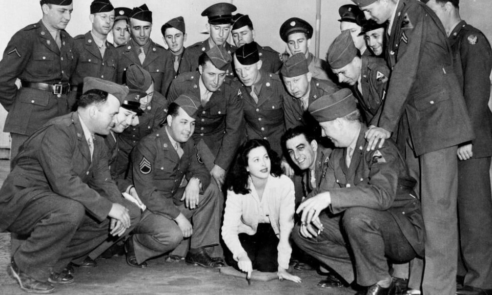 Hedy Lamarr sammen med amerikanske militære utenfor Hollywood-kantina under andre verdenskrig der kjendiser serverte mat og underholdt soldater før de skulle ut i krigen. Bildet er tatt i desember 1942. Foto: AP Hedy Lamarr sammen med amerikanske militære utenfor Hollywood-kantina under andre verdenskrig der kjendiser serverte mat og underholdt soldater før de skulle ut i krigen. Bildet er tatt i desember 1942. Foto: AP