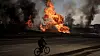 En ukrainer sykler forbi flammehavet i byen Kharkiv i Ukraina. Foto: Felipe Dana / AP/NTB