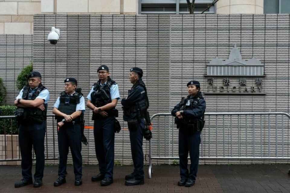 Politibetjenter holder vakt utenfor domstolen i Hongkong der 45 demokratiaktivister tirsdag fikk forkynt lange fengselsstraffer.