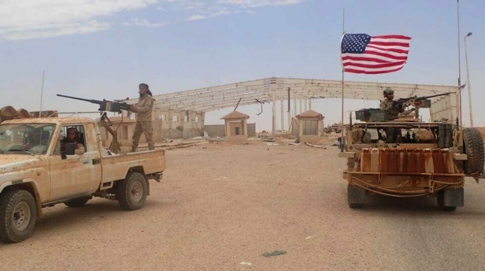 KRIGERE OG NARKOSMUGLERE: En syrisk kriger i opprørsgruppa Maghawir al-Thawra hever sitt automatvåpen, mens en amerikansk soldat står på sitt pansrede kjøretøy ved grenseovergangen Tanf mellom Irak og Syria, 23. mai 2017. I disse traktene trente norske soldater opprørsbevgelser i samarbeid med USA.