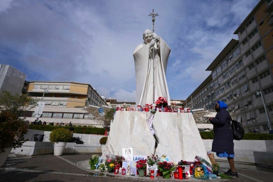 En person ber for pave Frans foran Gemelli-sykehuset i Roma, der paven har vært innlagt siden 14. februar.