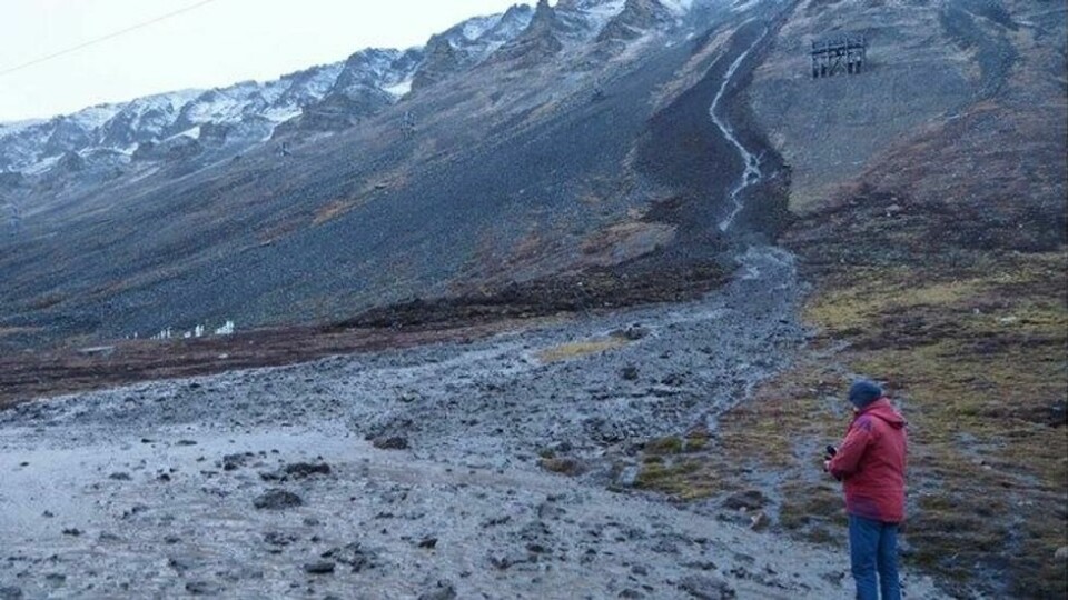 Skred i aktivlaget i fjellsiden i Longyeardalen i oktober 2016. Skredet kom ned bare 20 meter fra kirkegården, som også ses på bildet. Personen står på veibanen, som ble helt blokkert av skredmassene. Skred i aktivlaget i fjellsiden i Longyeardalen i oktober 2016. Skredet kom ned bare 20 meter fra kirkegården, som også ses på bildet. Personen står på veibanen, som ble helt blokkert av skredmassene. Foto: Privat