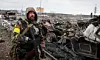 En væpnet mann står ved restene av et russisk militærkjøretøy i Bucha, nær hovedstaden Kyiv, Ukraina, tirsdag 1. mars 2022. Foto: Serhii Nuzhnenko / AP