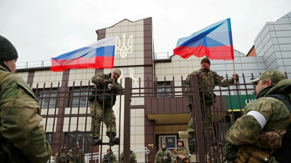 Pro-russiske soldater setter opp russiske flagg i utenfor en bank i Luhansk-området i Ukraina. Pro-russiske soldater setter opp russiske flagg i utenfor en bank i Luhansk-området i Ukraina. Foto: Alexander Ermochenko / Reuters/NTB