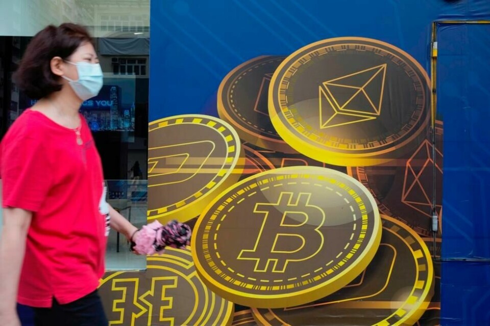 En kvinne passerer reklame for kryptovalutaen bitcoin i Hongkong. Utvinning av bitcoin krever enorme mengder energi er og er businessen er blitt en miljøversting. En kvinne passerer reklame for kryptovalutaen bitcoin i Hongkong. Utvinning av bitcoin krever enorme mengder energi er og er businessen er blitt en miljøversting. Foto: NTB / NTB