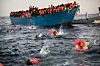 Migranter, de fleste fra Eritrea, hopper i vannet under en redningsoperasjon i Middelhavet utenfor kysten av Libya. Foto: Emilio Morenatti / AP / NTB scanpix Foto: NTB scanpix