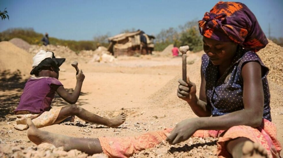 Dette bildet tatt 23. mai 2016 viser en kvinne og et barn som knuser steiner hentet opp fra en koboltgruve i Lubumbashi i Kongo.