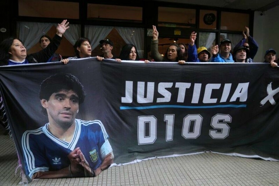 Fans av fotballikonet Diego Maradona holder her et banner utenfor rettsbygningen der sju helseansatte er tiltalt for å ha opptrådt grovt uaktsomt i forkant av Maradonas død. På banneret står det «Rettferdig for Gud».