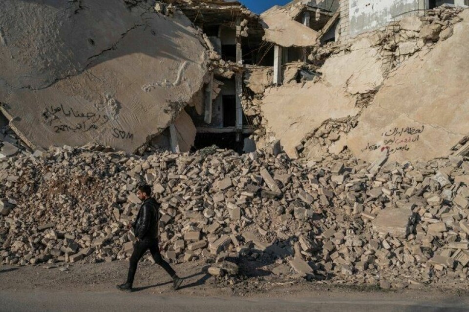 En mann går forbi et ødelagt hus i byen Idlib i Syria.