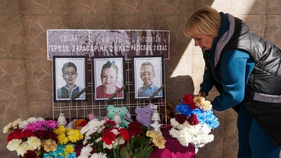 En ukrainsk kvinne legger ned blomster foran bilder av tre av de ni barna som ble drept i et russisk luftangrep mot byen Kryvyj Rih forrige uke.