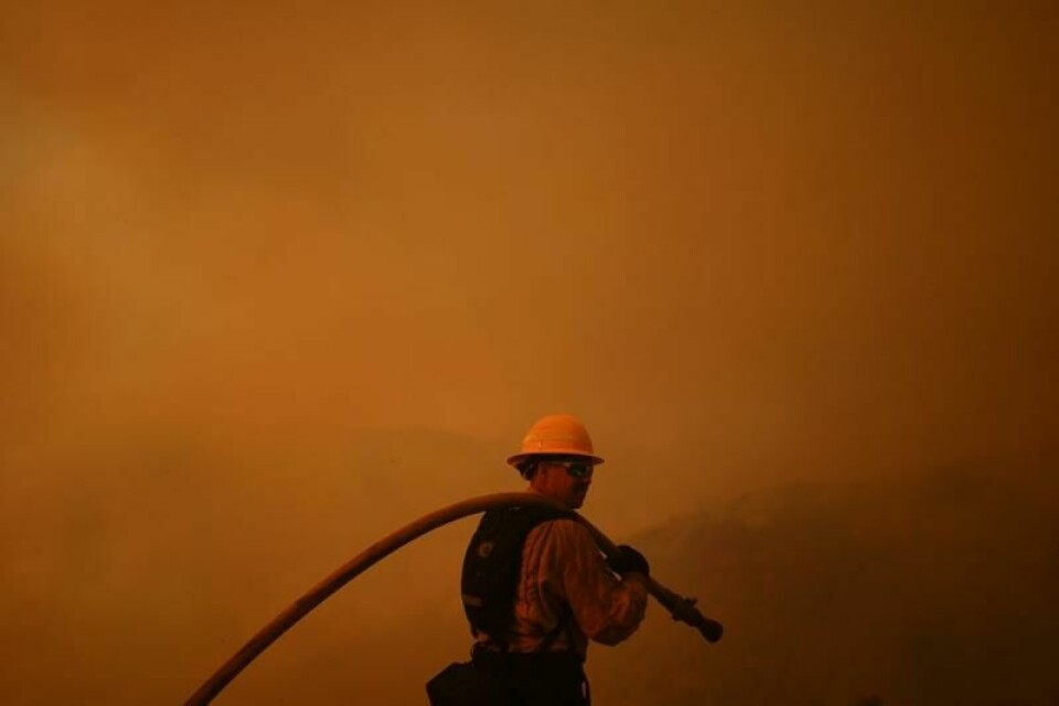 En brannmann jobber med slukking i Mandeville Canyon i Los Angeles lørdag.