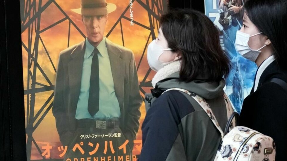 Folk går forbi en plakat som promoterer premieren av «Oppenheimer», filmen om mannen som kalles «atombombens far». Filmen hadde premiere i Japan fredag. Foto: Eugene Hoshiko / AP / NTB