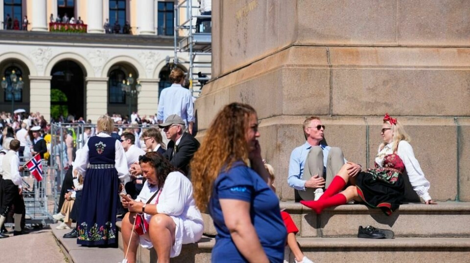 Det er godt og varmt i Oslo fredag. Cecilie Schibstad med røde strømper og Jon Gløersen fra Risør lufter føttene ved Karl Johan-statuen utenfor slottet. Foto: Heiko Junge / NTB