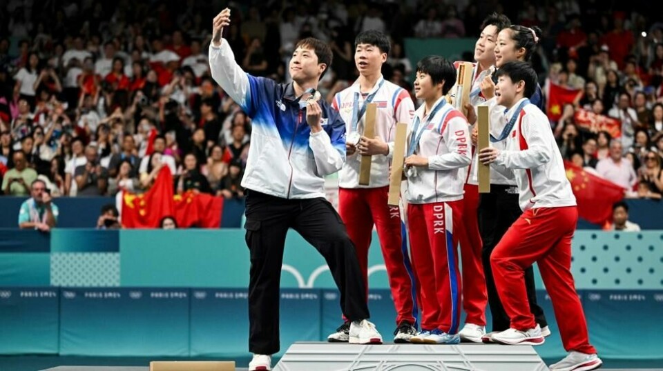 Nordkoreanerne Ri Jong-sik (nummer to fra venstre) og Kim Kum-yong (i midten) stiller opp på en selfie sammen med de andre medaljevinnerne i mixed double-konkurransen i bordtennis under sommerens OL i Paris. Det skulle de nå kanskje ønske de ikke hadde gjort.