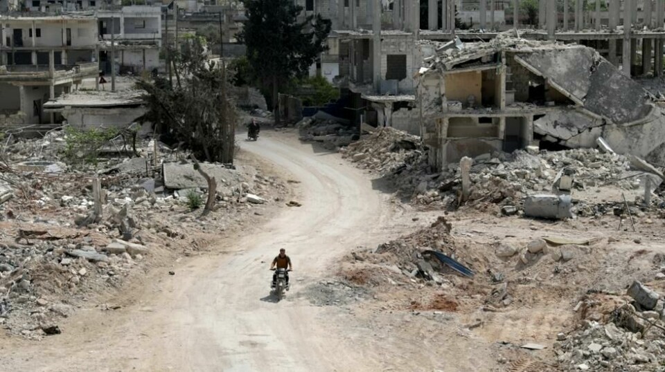 En mann kjører motorsykkel forbi ødelagte hus i den opprørerkontrollerte byen Nairab i Idlib-provinsen. April 2020. NTB Scanpix/Reuters.