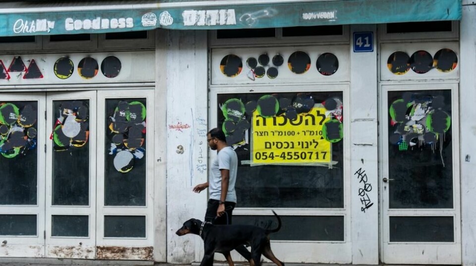 Mange butikker i Israel har måttet stenge på grunn av krigen og de problemene den skaper for økonomisk aktivitet. Her går en mann forbi en stengt butikk i Tel Aviv. Foto: Ariel Schalit / AP / NTB