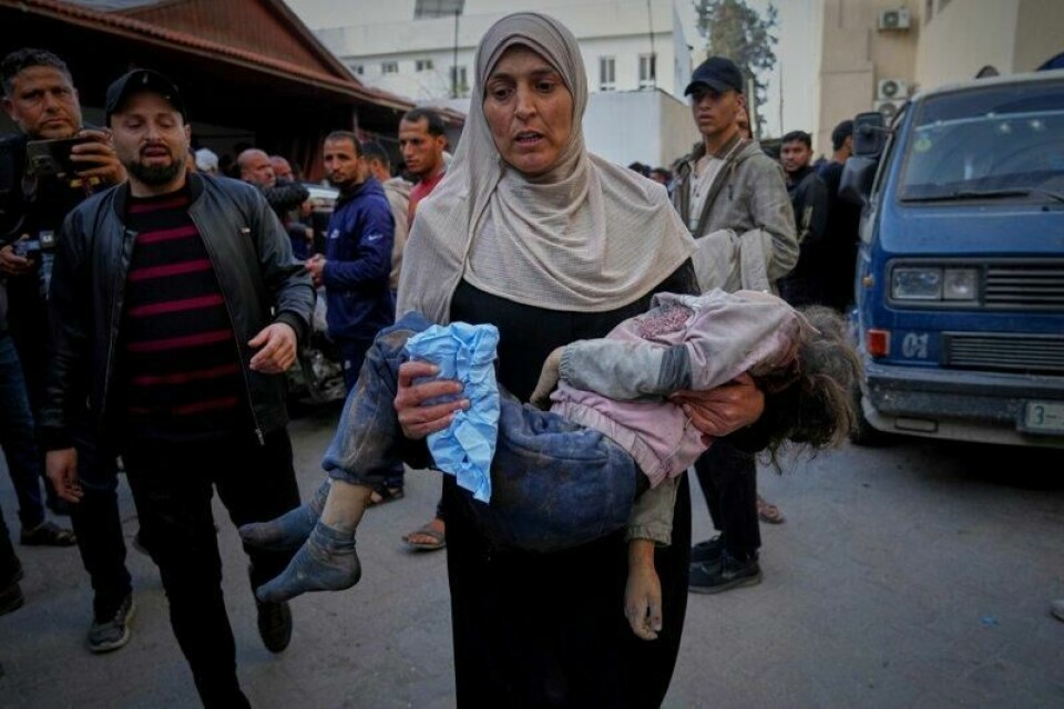 En palestinsk kvinne bærer et av ofrene for nattens israelske angrep på Gazastripen, der over 400 mennesker ifølge helsemyndighetene ble drept.