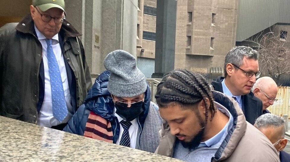 Joe Lewis (i midten med grå lue) ble skjermet mot fotografene da han forlot retten i New York etter å erklært seg skyldig i innsidehandel. Foto: Larry Neumeister / AP / NTB