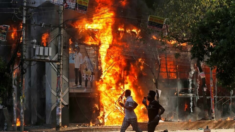 Demonstranter løper forbi en butikk som står i brann i Dhaka. Foto: Rajib Dhar / AP / NTB Demonstranter løper forbi en butikk som står i brann i Dhaka. Foto: Rajib Dhar / AP / NTB