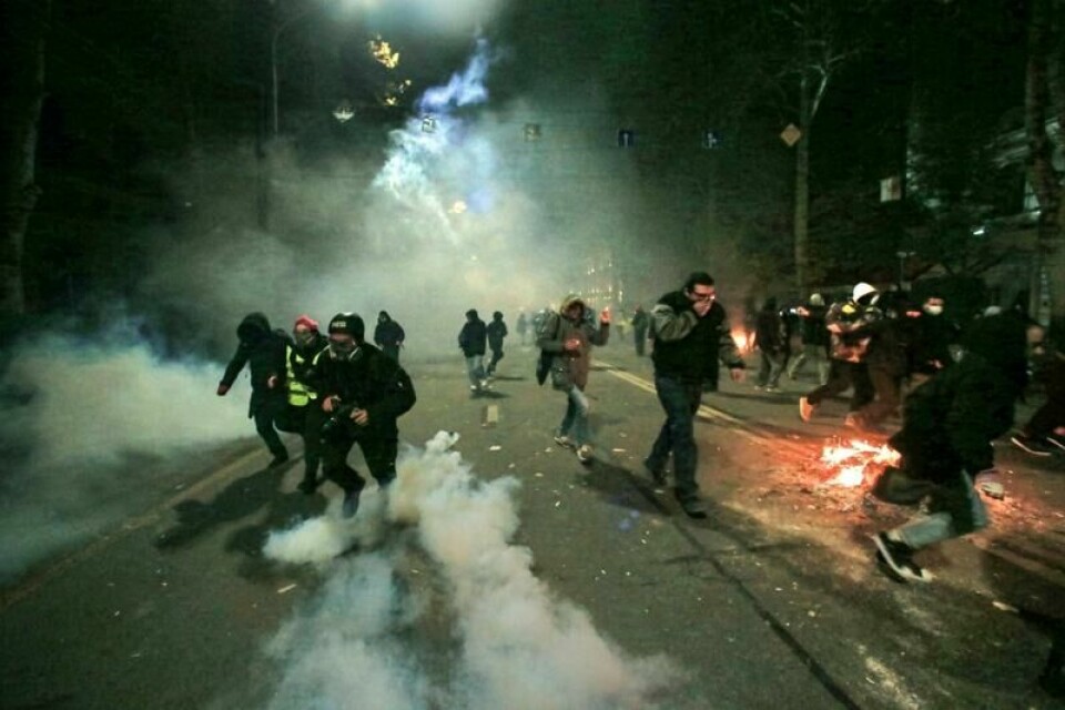Demonstranter løper unna politiet utenfor nasjonalforsamlingen i Georgias hovedstad Tbilisi natt til søndag.
