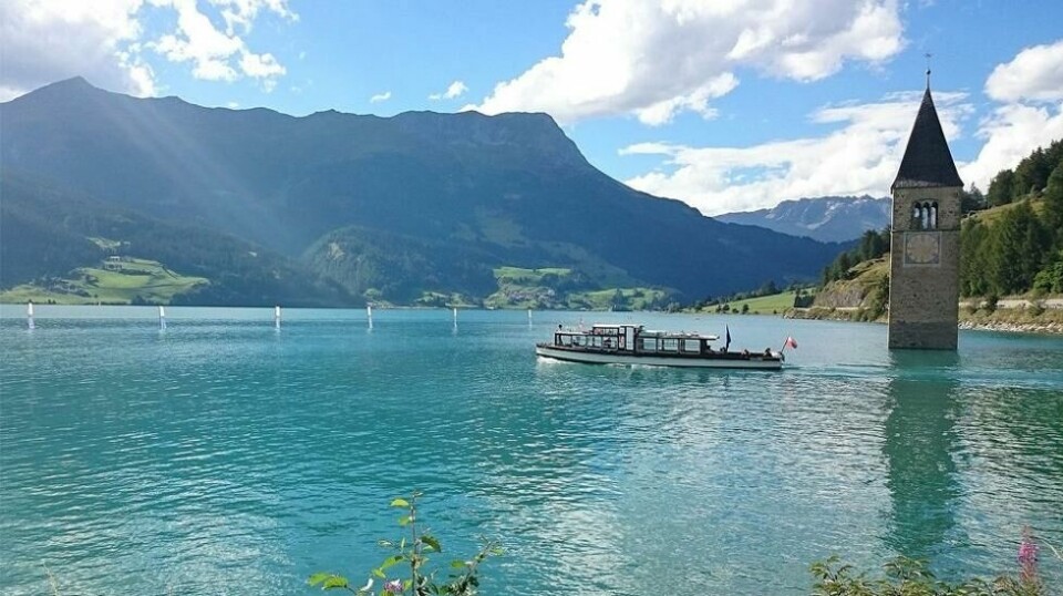 I Sør-Tyrol helt nord i Italia, på grensen mot Østerrike, står et gammelt kirketårn i ensom majestet midt ute i en innsjø. Dette er den eneste synlige resten av den italienske landsbyen Graun, som i 1950 måtte gi tapt da et kraftselskap demmet opp innsjøen Reschensee. Foto: Noclador / wikipedia.org.