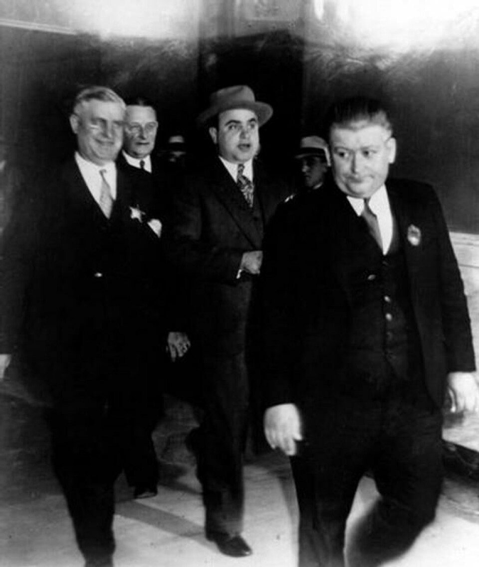 24. oktober 1931 fikk endelig påtalemyndighetene has på gangsterkongen Al Capone (midten). Her forlater han rettssalen hvor han ble dømt til 11 års fengsel for skatteunndragelser. 24. oktober 1931 fikk endelig påtalemyndighetene has på gangsterkongen Al Capone (midten). Her forlater han rettssalen hvor han ble dømt til 11 års fengsel for skatteunndragelser. Foto: AP / NTB