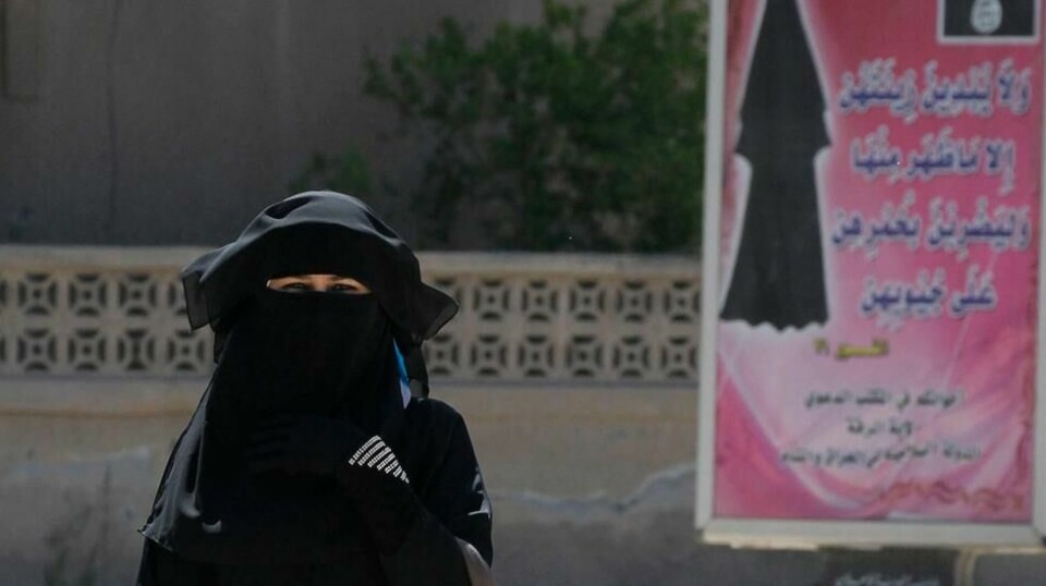IS-hovedstaden Raqqa i 2014: En kvinne passerer en plakat som siterer Koranen og påbyr bruken av religiøse klær.