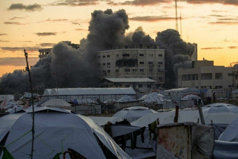 Bak en teltleir i Gaza by stiger det opp massiv, svart røyk etter at en bygning ble truffet i et israelsk angrep 22. mars. Til tross for Israels ordre om å komme seg ut av byen og nye angrep, velger mange palestinere å bli værende.
