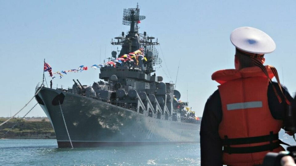 En ung russisk sjømann speider utover sjøen. ved havnen i Sevastopol. I bakgrunn ruver flaggskipet «Moskva».