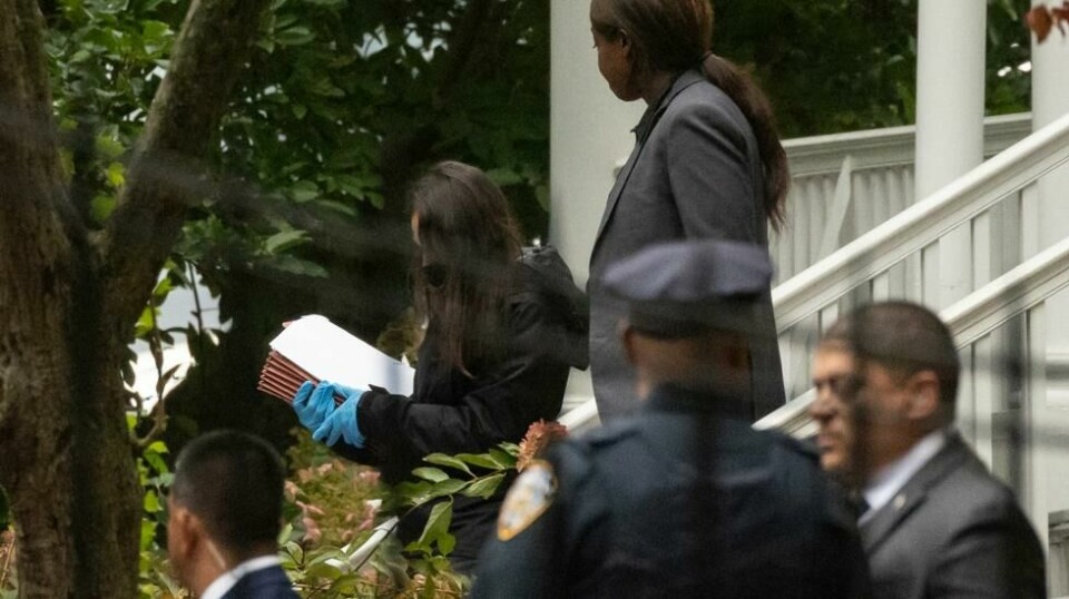 En person med hansker bærer ut mapper fra New York City-ordfører Eric Adams' offisielle bolig torsdag morgen. Foto: Yuki Iwamura / AP / NTB