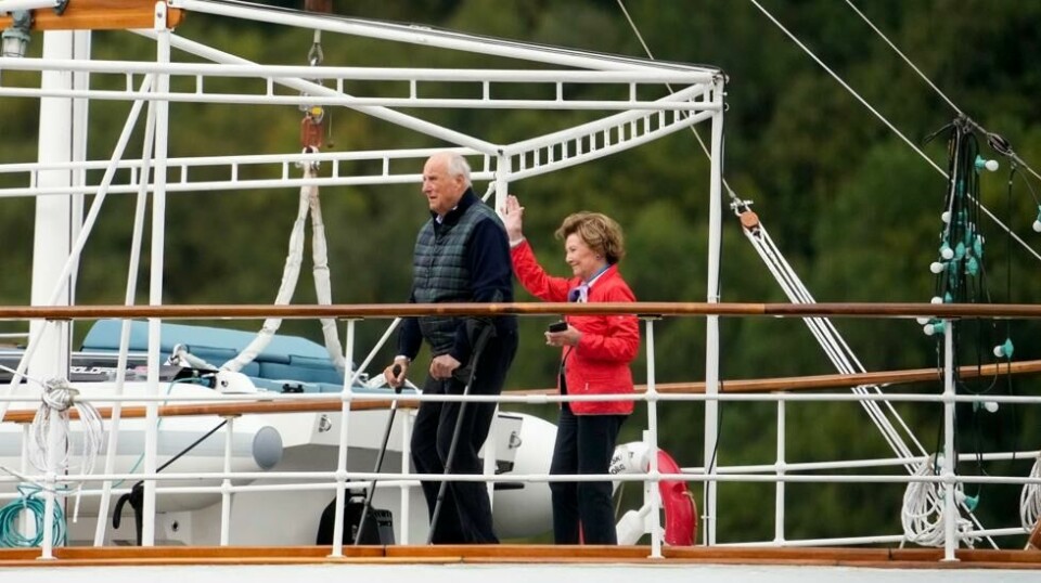 Kong Harald og dronning Sonja hilser på båtene som frakter gjestene til bryllupsfeiring i Geiranger. Foto: Heiko Junge / NTB